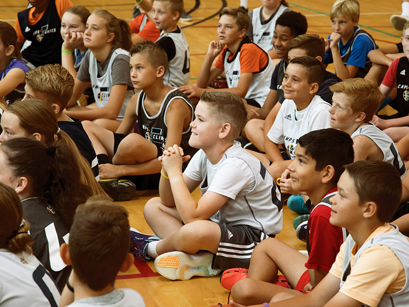 Group of Jazz Youth kids sitting in a group listening to a coach speak